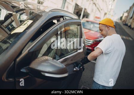 Junger behinderter Mann, der die Tür des Autos mit einer künstlichen prothetischen Hand öffnet Stockfoto