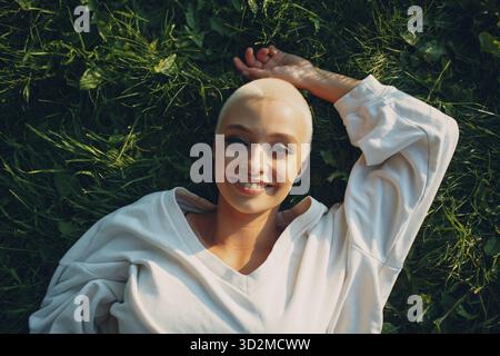 Porträt eines jungen lächelnden europäischen Wimpernschattens Kurzhaarige Frau liegt auf grüner Graswiese Sommerpark über dem Dach aus der Luft. Schön Stockfoto