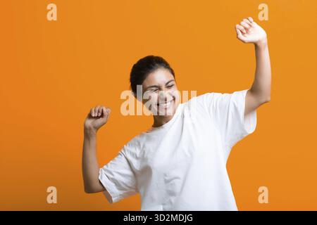 Porträt einer jungen erwachsenen glücklich tanzenden indischen Frau in T-Shirt Stockfoto