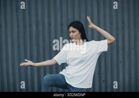 Asiatische junge Frau, die im Sommer im Freien Qigong- oder Wushu-Übungen macht Stockfoto