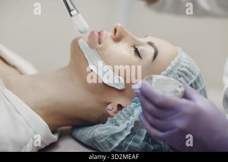 Junge Frau, die im Beauty Spa eine Maske aus Lehm auf das Gesicht aufführt Stockfoto