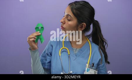 Die Ärztin in Uniform hält ein grünes Band über die violette Wand, das Bewusstsein symbolisiert. Stockfoto