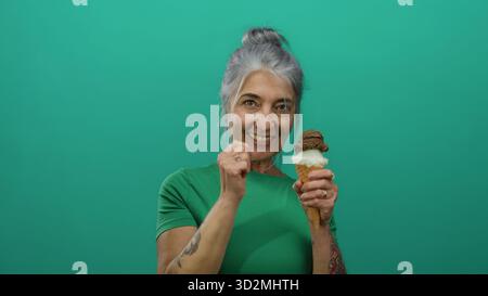 Frau, die mit Eis vor einem leuchtend grünen Hintergrund feiert und Freude und köstliche Genüsse in einer isolierten Umgebung präsentiert, in grünem Shi Stockfoto