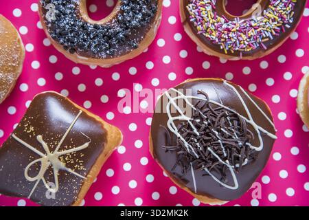 Handwerkliche Donuts auf rosafarbenem Hintergrund von oben Stockfoto