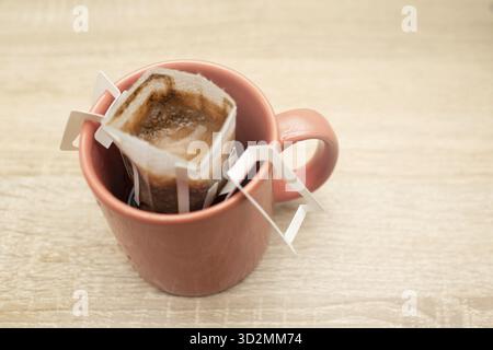 Kaffeetrinken in der Tasse verpacken. Alternativer Braukaffee in Papierfiltertüten auf Glas Stockfoto