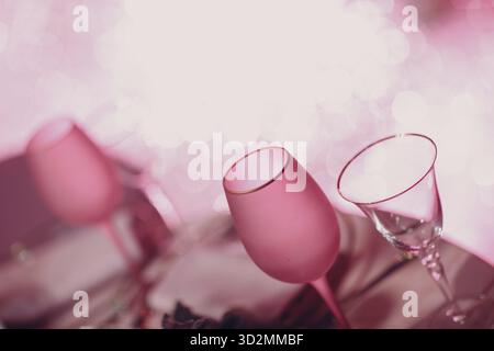 Zwei leere Champagnergläser, rosafarbener Champagner auf dem Tisch mit funkelnden Bokeh-Lichtern auf einem Hintergrund Stockfoto