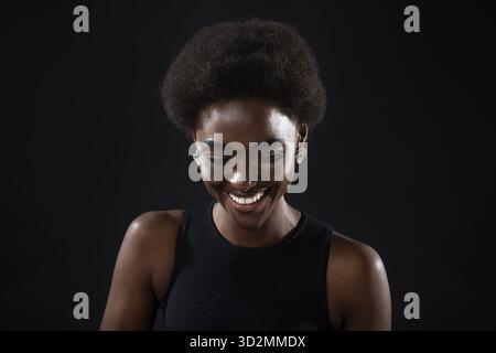 Junge schwarze positive afroamerikanische Frau lachend Porträt auf schwarzem Hintergrund Stockfoto