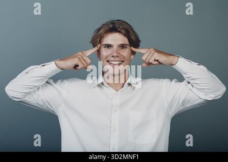 Porträt europäischer junger positiv denkender Mann Porträt mit den Handfingern am Kopf Stockfoto