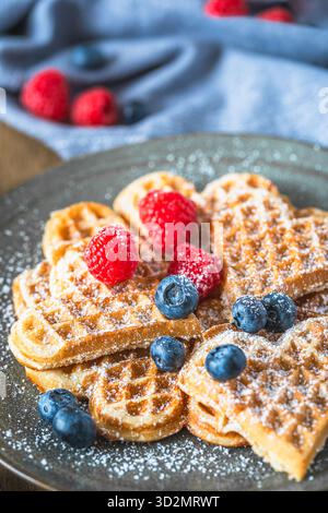 Hausgemachte Waffeln mit Puderzucker und Beeren Holztisch, vertikal Stockfoto