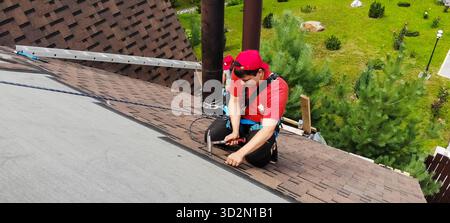 Moskau, Russland - 21. August 2019: Arbeiter macht die Installation des Daches des Hauses. Installation von Metallfliesen, Schneehaltern und anderen Elementen Stockfoto