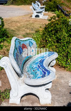 Leere Bank, dekorierte Bank mit bunten Mosaikfliesen in Brenton on Sea, Südafrika, an einem sonnigen Nachmittag im Frühling. Vertikal. Stockfoto
