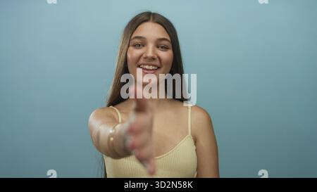 Teen Girl streckt die Hand nach vorne für Handschlag mit warmem Lächeln im Studio-Mittelrahmen; freundliche Begrüßung. Stockfoto
