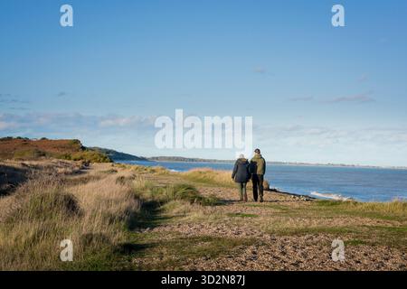 Junge Paare Küste Großbritannien, Rückansicht von zwei jungen Leuten, die zusammen am Strand von Dunwich in Suffolk, England, Vereinigtes Königreich laufen. Stockfoto