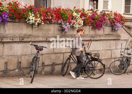 Linz, Österreich - 2. Juli 2019: Junger Mann verriegelt Fahrrad auf dem Hauptplatz der Stadt Linz. Stockfoto