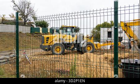 Orangener Bulldozer auf einer Baustelle an einem bewölkten Tag. Baumaschinen bewegen Sand während der Arbeit. Stockfoto