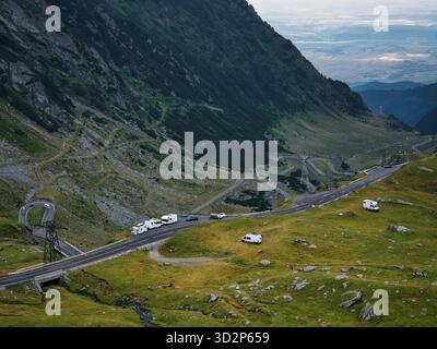 Gewundene Bergstraße auf der Transfăgărășan-Autobahn in Rumänien, mit Autos fahren durch die dramatische Landschaft des alpinen Tals in den Südkarpaten Stockfoto