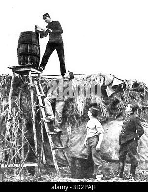 Improvisierte Duschkonstruktion an der Front (Le Miroir, 11. Juli 1915) französische Soldaten bauen während des Ersten Weltkriegs eine provisorische Dusche aus Fässern und Leitern in einem Feldlager. Das Bild zeigt den Einfallsreichtum und die Moral der Truppen, die unter rauen Bedingungen in der Nähe der Front Hygiene aufrechterhalten. Stockfoto