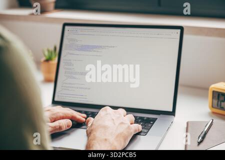 Nahaufnahme von männlichen Händen, die Code auf einem Laptop im Heimbüro eingeben, Konzept der Programmierung, Softwareentwicklung und digitale Fernarbeit. Selektiv Stockfoto