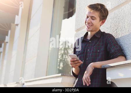 Junger lächelnder Mann mit Smartphone Stockfoto