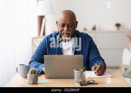Reifer Geschäftsmann, der tagsüber online arbeitet und Notizen im Modern Office macht Stockfoto