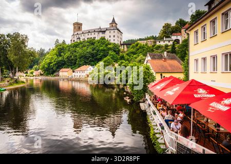 Café am Flussufer am Ufer des Flusses Vitava vor der Burg Rožmberk, einer der ältesten Schlösser in Tschechien. Stockfoto