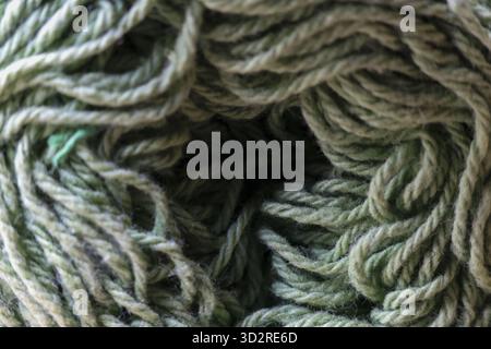 Gemütlicher Makrohintergrund aus weichem grünem Garn. Wollkugel zum Stricken oder Häkeln. Handgefertigtes Material, das ein Gefühl von Wärme und Kreativität vermittelt Stockfoto