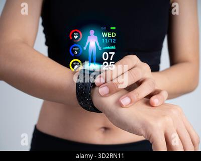 Nahaufnahme einer Frau in schwarzem Sport-BH mit intelligenter Fitness-Uhr am Handgelenk mit holografischer Gesundheitsdatenanzeige, Tracking-Schritte, Herzfrequenz und Kalorien Stockfoto