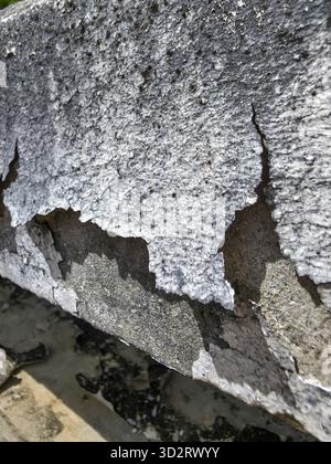 Beschädigte alte Betonwand mit gebrochener, gerissener Oberfläche, die Verfall zeigt. Eine abstrakte Hintergrundstruktur zeigt ein Schrammmuster aus dem Baumaterial Stockfoto