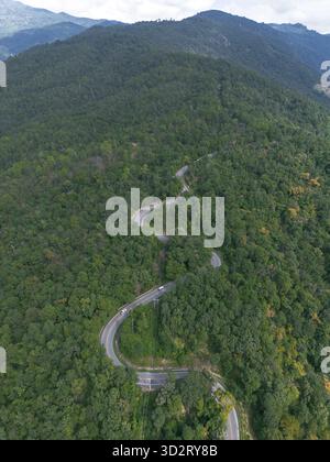 Aus der Vogelperspektive zieht sich die gewundene Straße durch weite grüne Wälder und schlängelt sich durch die majestätische Berglandschaft. Die malerische Reise weckt ein Gefühl von Ruhe und A Stockfoto