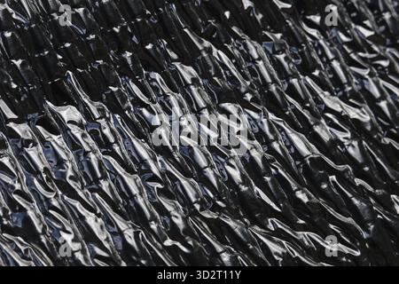Abstrakter Texturhintergrund mit zerknittertem Muster auf schwarzer und silberner Metallfolie. Modernes, industrielles Material für Design und Details mit Rough Stockfoto