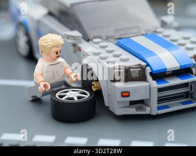 Tambov, Russische Föderation – 21. August 2025 Lego Brian OConner Minifigur wechselt das Rad seines Lego Speed Champions Nissan Skyline GT-R (R34). 2 Stockfoto