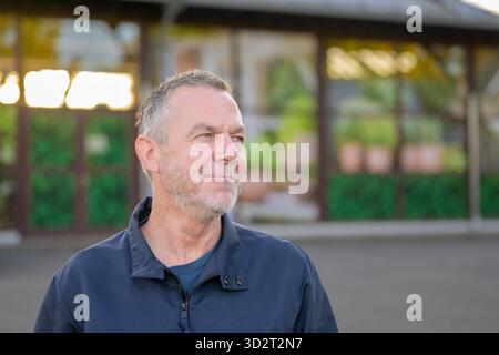 Porträt eines selbstbewussten, Reifen Mannes, der bei natürlichem Tageslicht zur Seite blickt, mit einem nachdenklichen Ausdruck. Stockfoto