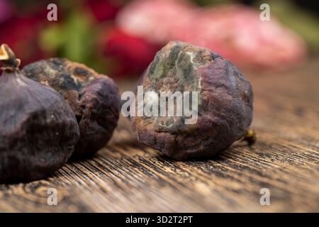 Ganze überreife und verdorbene Feigen auf dem Tisch, schimmelige verdorbene Feigen auf dem Holztisch Stockfoto