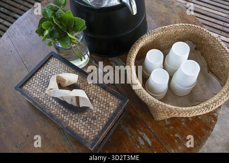 Ruhiger, entspannender, rustikaler Holztisch mit gewebtem Korb mit weißen Tassen, Tablett und frischen Minzblättern im Glas. Ruhige und ruhige Atmosphäre Stockfoto