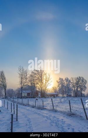 Sonnensäule über einem Ferienhaus in einer winterlichen ländlichen Landschaft Stockfoto