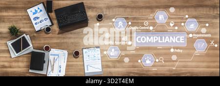 Ein moderner Büroarbeitsplatz mit Compliance-Konzepten wie Qualitätssicherung und -Sicherung, die visuell über einem Holztisch mit verschiedenen Unterlagen dargestellt werden Stockfoto