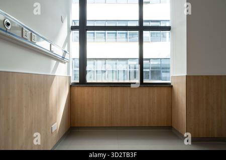 Krankenhauszimmerecke mit Holzpaneelen und großen Fenstern Stockfoto