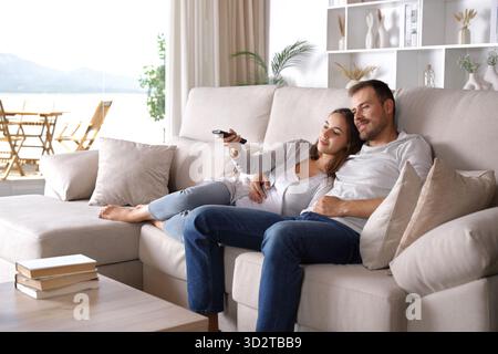 Ein zufriedenes Paar, das zusammen auf einer Couch zu Hause fernsieht Stockfoto