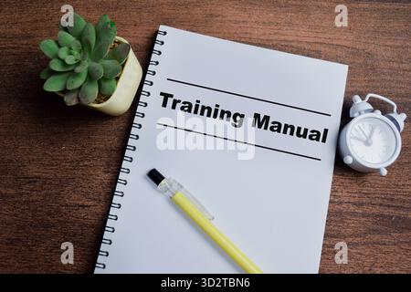 Konzept des Schulungshandbuchs Schreiben auf Buch isoliert auf Holztisch. Stockfoto
