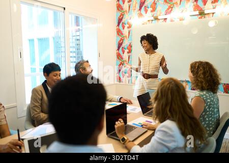 Schwarze Geschäftsfrau, die verschiedene Teamsitzungen im Büro leitet Stockfoto