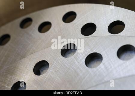 Nahaufnahme des industriellen Hintergrunds einer Metallscheibe mit gebohrtem Lochmuster. Die Struktur aus gebürstetem Stahl vermittelt ein Gefühl von Kraft und Präzision in Automobilmaschinen Stockfoto