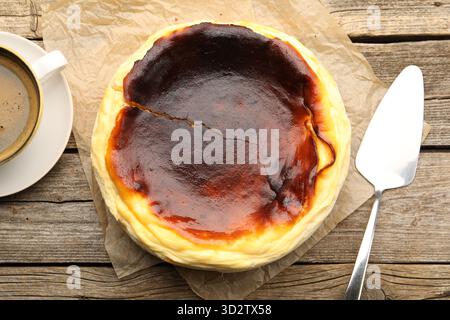Leckerer baskischer Käsekuchen, Tasse Kaffee und Spatel auf Holztisch, flacher Lay Stockfoto