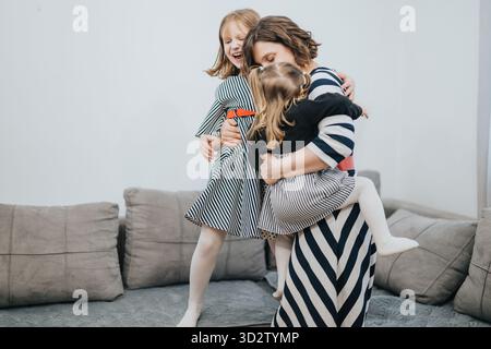 Liebende Mutter mit zwei Töchtern, die zu Hause fröhliche Momente verbringen Stockfoto
