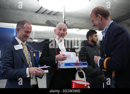 Sprecher des House of Commons, Sir Lindsay Hoyle (Mitte), zusammen mit dem Freiwilligen Christopher Leader (links), der Mohnblumen für den Royal British Legion Poppy Appeal verkauft, an der U-Bahn-Station Westminster in London. Bilddatum: Montag, 3. November 2025. Stockfoto