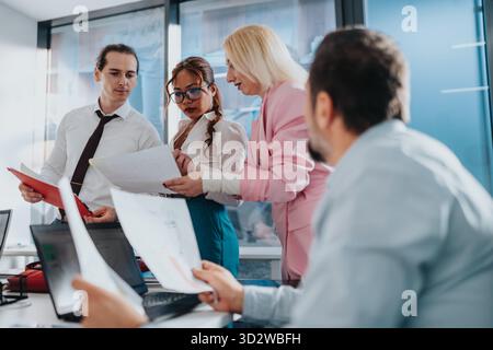 Ein Team von Fachleuten arbeitet während eines Geschäftstreffens in einem modernen Büro an Dokumenten zusammen Stockfoto