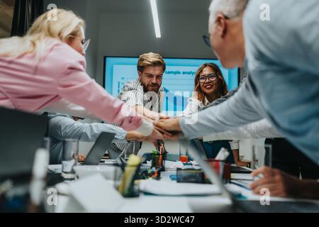 Ein Team aus verschiedenen Fachleuten in einem modernen Büro schließt sich für ein gemeinsames Meeting zusammen Stockfoto