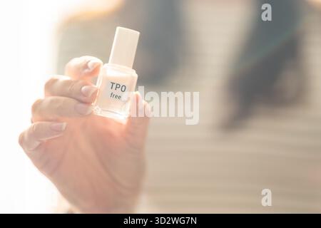 Frau, die eine Flasche TPO-freier gelpolitur in hellem Tageslicht hält. Sicheres Maniküre-Produkt ohne Trimethylbenzoyl-Diphenylphosphin-Oxid für Stockfoto