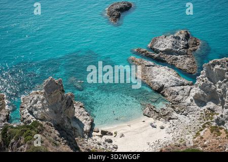 Blick aus der Vogelperspektive auf den kleinen Sandstrand und das türkisfarbene Meer in der Nähe der felsigen Küste von Capo Vaticano, Süditalien. Stockfoto