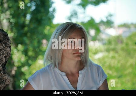 Porträt einer nachdenklichen Frau in weißem Hemd draußen bei natürlichem Licht Stockfoto