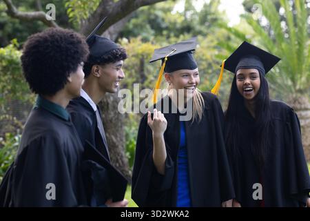 Absolventen in Mützen und Kleidern, die gemeinsam im Freien fröhlich feiern. Abschluss, Erfolg, Zeremonie, Universität, Feier, Erfolg || Modell veröffentlicht Stockfoto